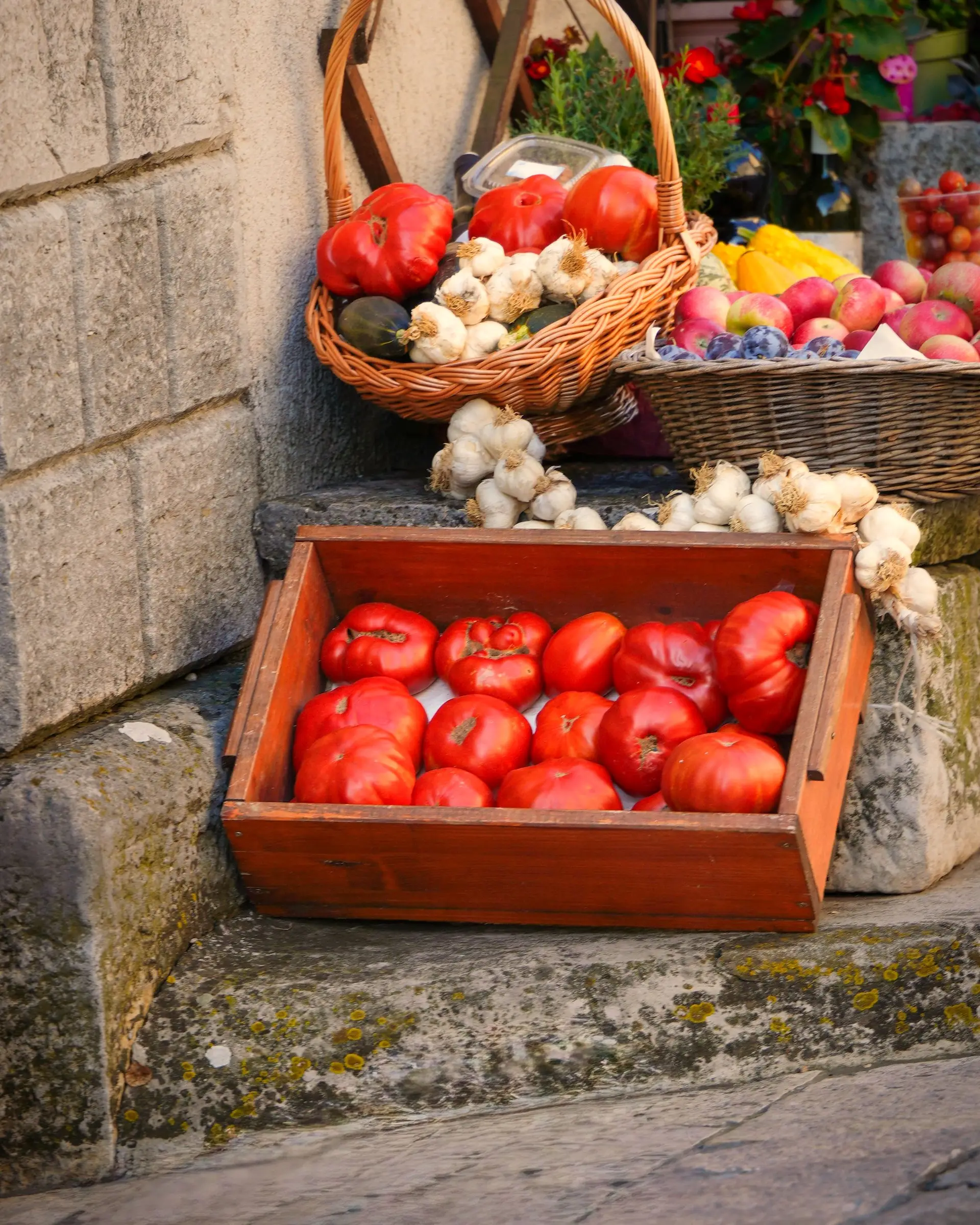 Tomates, ajos y verduras en cajas de madera en un mercado