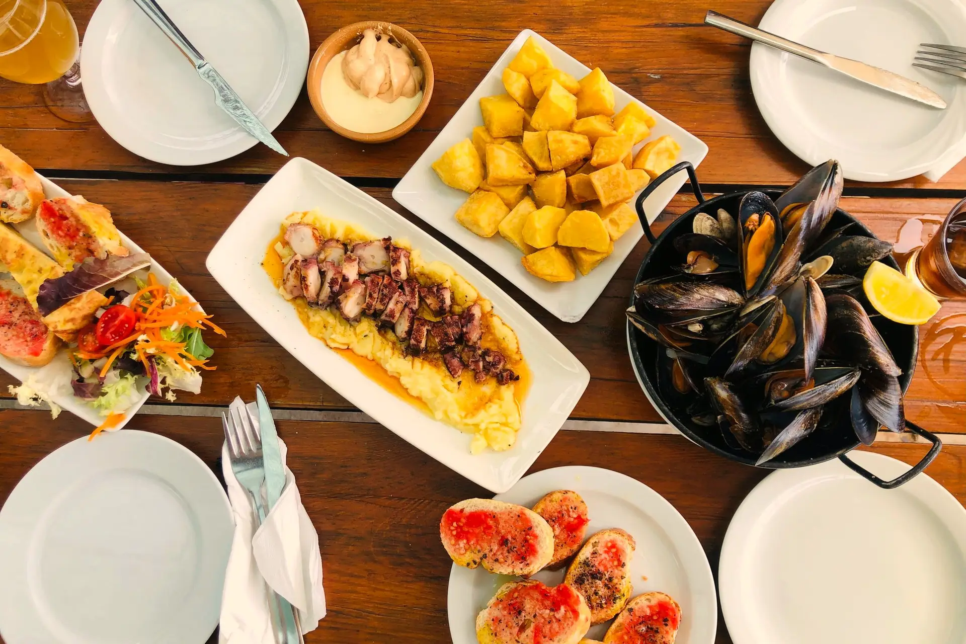 Mesa con mejillones, patatas y pan con tomate vista desde arriba